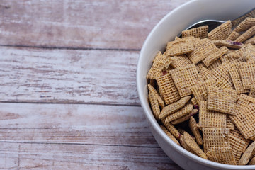 Breakfast cereal in white bowl with frozen blueberries and wood table background