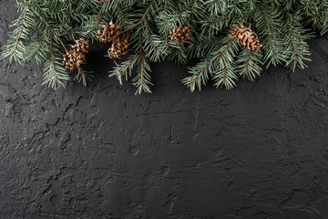 Christmas Fir branches with pine cones on dark black background. Xmas and Happy New Year card, bokeh, sparking, glowing