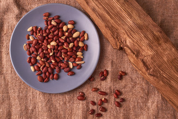 Fried Roasted peanut seed on blue plate on sackcloth background. Space for text. Copyspace