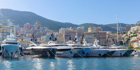 Yachts moored in Monaco harbour  with Monaco landscape on a background - obrazy, fototapety, plakaty