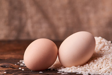 Bunch of rice and uncooced eggs on wooden table. Concept health food