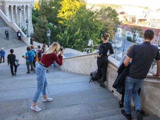Budapest, Hungary, 09.27.2018. Girl with a camera taking pictures of a friend on the stairs of the Fishing Fort in Budapest