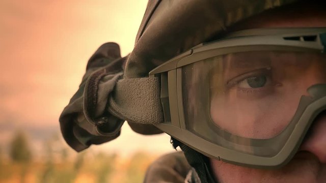 Close-up right eye of caucasian male in military helmet, looking straight at camera standing outdoor, in sunlights isolated