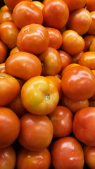 Group of orange tomatoes stacked on a supermarket shelf. Bright, delicious and juicy. Solanum lycopersicum fruit vegetable with sunning color.