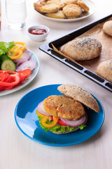 Healthy vegan burger with chickpea fritters, vegetables and whole-wheat bun with sesame and poppy seeds on white table for breakfast. Cooking, recipe