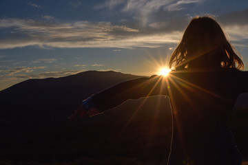 Fototapeta na wymiar Girl hugging a sunset. Serenity and peace