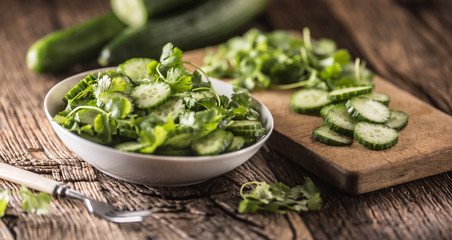 Sliced cucumber on a plate with parsley herb on rustic oak wood.