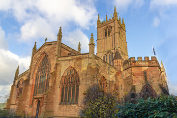 Saint Laurence Church in Ludlow, England is architecturally striking under a blue sky and glows in...