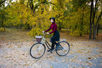young woman riding on retro bicycle in the autumn park	