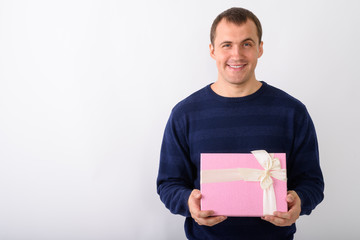 Studio shot of young happy muscular man smiling while holding gi