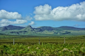 Fototapeta na wymiar Weitläufige grüne Weidelandsschaft führt zu einer weichen Berglandschaft darüber blauer Himmel mit weissen Wolken Schottland