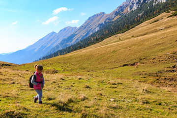 Fototapeta na wymiar Joung girl walking on the mountain pasture under the Kosuta ridge in Karavanke range mountains, Slovenia