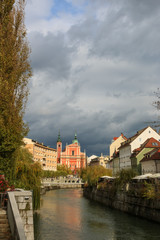 View of Ljubljanica river in old city with dark stormy clouds in the background on an autumn day, Ljubljana, Slovenia