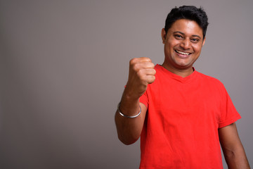 Portrait of young Indian man against gray background