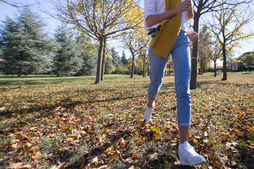 autumn fun young woman in blue jeans running on brown leaves in park low section crop
