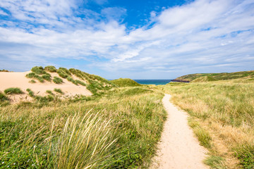 Scenic landscape of Pembrokeshire coast, Uk.Coastal path on sand dunes covered with grass patches leading to beautiful beach.