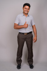 Portrait of young Indian businessman against gray background