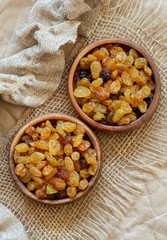 Golden raisins in wood bowls on burlap.