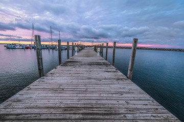 Fototapeta premium Panoramic Recreational Boating Background. Long wooden dock and marina with variety of recreational boats at a state owned harbor on Lake Huron in Michigan.