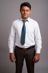 Portrait of young Indian businessman against gray background