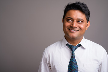 Portrait of young Indian businessman against gray background