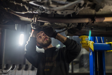 Young caucasian man repairing car with professional tools 
