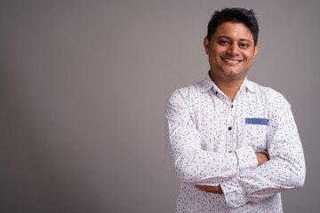 Portrait of young Indian businessman against gray background
