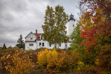 Fototapeta premium Michigan Upper Peninsula Autumn Landscape. Point Iroquois Lighthouse surrounded by beautiful vibrant fall foliage on the shores of Lake Superior. Point Iroquois is part of the Hiawatha National Forest
