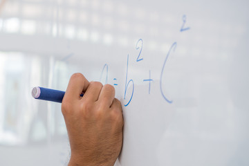 Hand Asian solving solution Math formulas, doing mathermatics problem on whiteboard in classroom at high school. Back to School concept