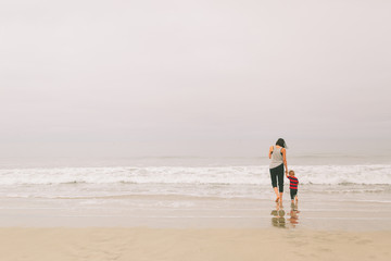 a mother and son walking on the beach