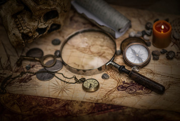 Vintage magnifying glass, compass, old key and a pocket watch lying on an old map