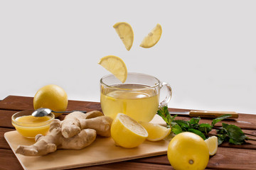 making lemon and ginger root tea with honey and mint on wooden cutting board