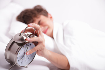 Boy trying to turn off his alarm clock