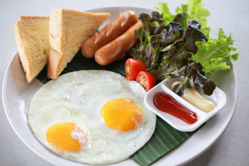 Plate of breakfast with fried eggs, sausage and vegetables.