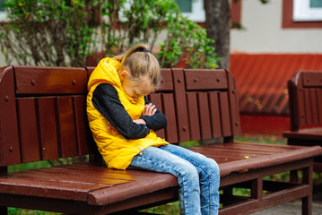 Fototapeta premium Teenager girl sitting alone on a bench and crying