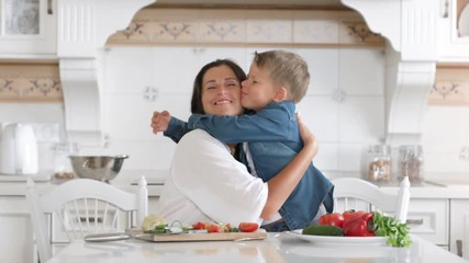 Caring young mother and cute little son showing tenderness and love hugging in home kitchen - Powered by Adobe