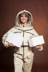 Fototapeta premium The girl the Beekeeper in a protective suit holds boxes in hand