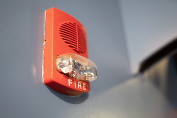 Red fire alarm sensor and smoke detector on the blue wall.