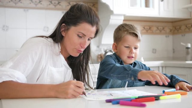 Mom and son draw image on paper together using multicolored felt-tip pen