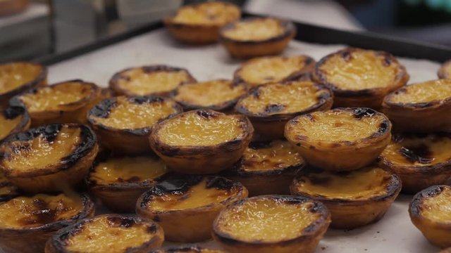 Traditional Portuguese egg hands take tart pasty cakes, dessert Pasteis de nata with different portuguese pastry on the cafe store window, pastel de nata