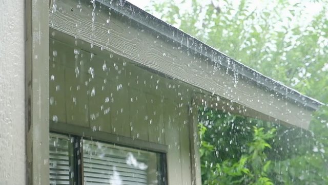 Slow motion of heavy rain falling on house roof