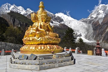 Golden Buddhist Statue with Mt. Gongga in the background, Sichuan, China.  