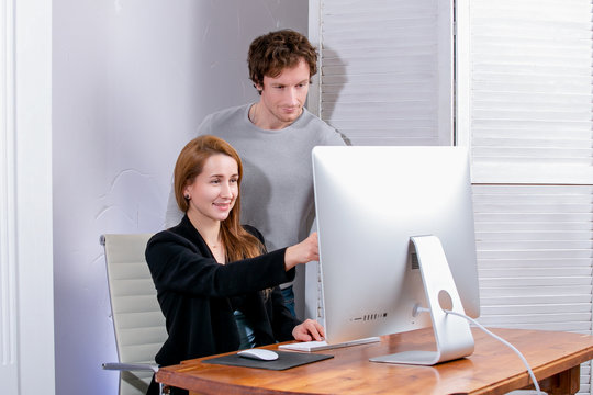 Portrait of young successful woman and man at office. They looks at the display, doing office work. Black Friday or Cyber Monday. Browsing or selecting items, making a deal, online shopping, good mood