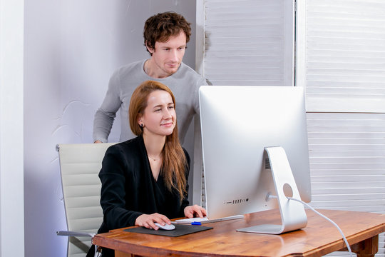 Portrait of young successful woman and man at office. They looks at the display, doing office work. Black Friday or Cyber Monday. Browsing or selecting items, making a deal, online shopping, good mood