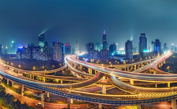 View on famous highway intersection in Shanghai, China, with illuminated highways and skyscrapers.