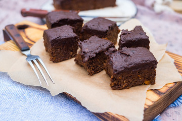 Vegan chocolate sweet brownie cake on wooden kitchen board and parchment paper. Pumpkin, cacao powder, Iranian dates. No bake. Vegetarian raw dessert piece. Paleo diet. Healthy food
