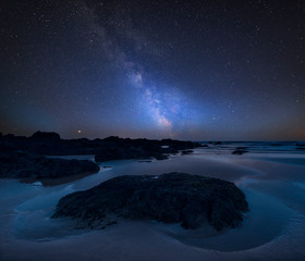 Vibrant Milky Way composite image over landscape of Freshwater West beach on Pembrokeshire Coast in...