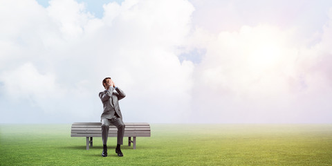 Young man in summer park on bench do not want to see anything