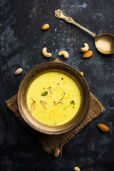 Basundi Or Rabri is an Indian sweet popular in Gujarat and Maharashtra. It is a sweetened condensed milk. Garnished with Dry fruits and Saffron. Served in a bowl over moody background. Selective focus