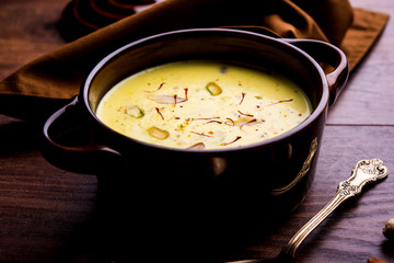 Basundi Or Rabri is an Indian sweet popular in Gujarat and Maharashtra. It is a sweetened condensed milk. Garnished with Dry fruits and Saffron. Served in a bowl over moody background. Selective focus